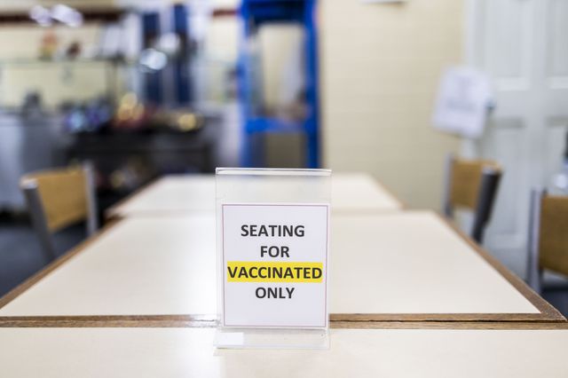A view of a sign on a table inside a restaurant explaining the city's current vaccination requirements.